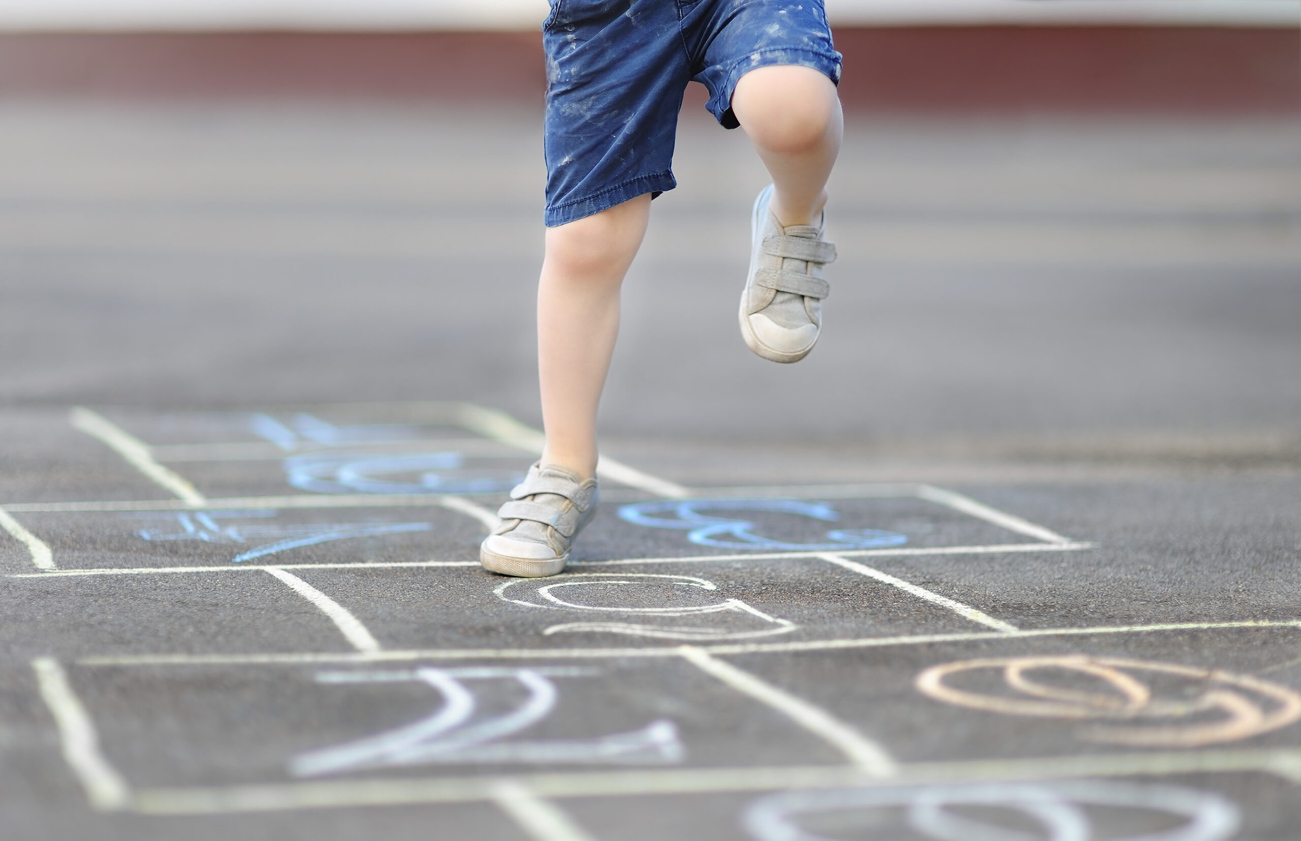 Close up of young boys legs playing hopscotch
