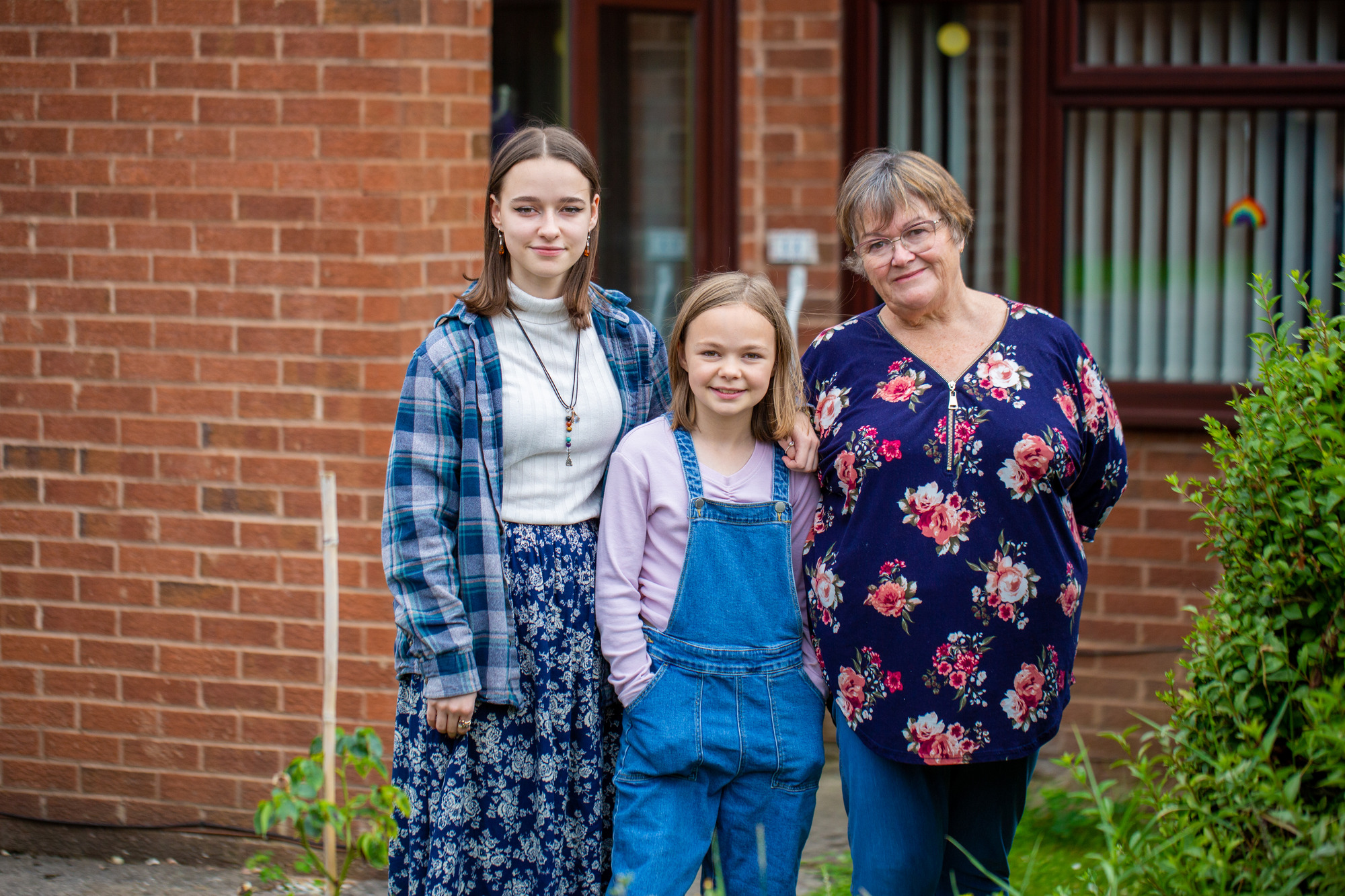 woman and two children posing for a photo outside a house